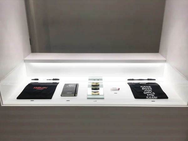 Books and prism sculptures arranged inside a white exhibition case.