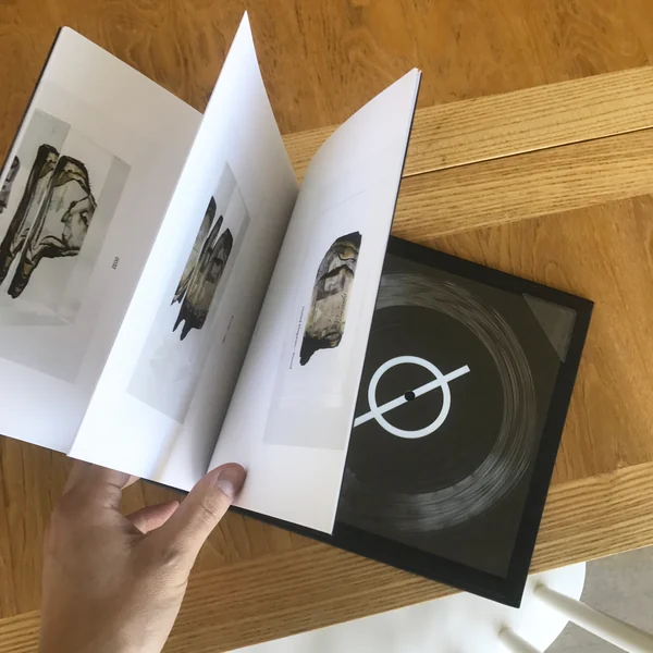 An open art book alongside a black flexi record marked with the Ø symbol.
