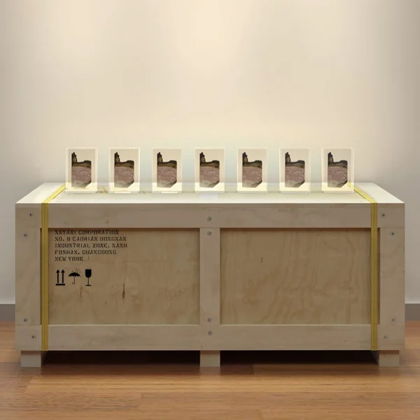 A row of small prism sculptures displayed on a pale wooden plinth.